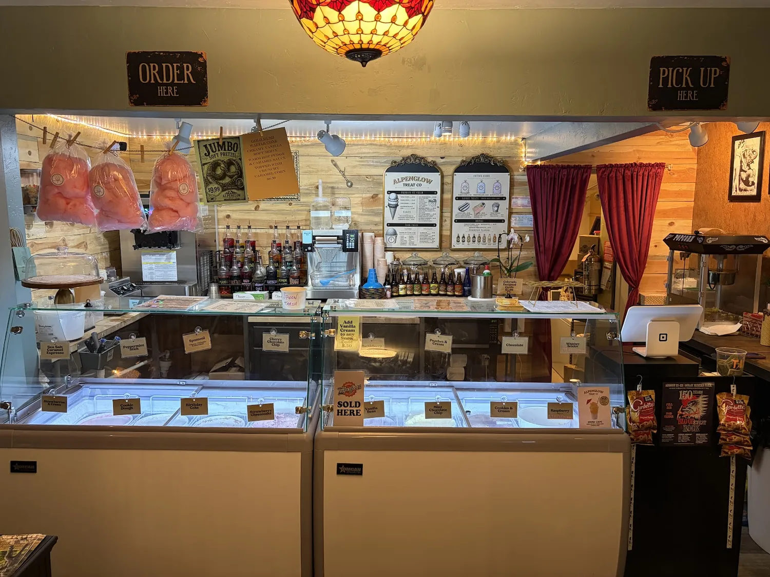 Alpenglow Treat Co counter with ice cream freezers, cotton candy, and order signs