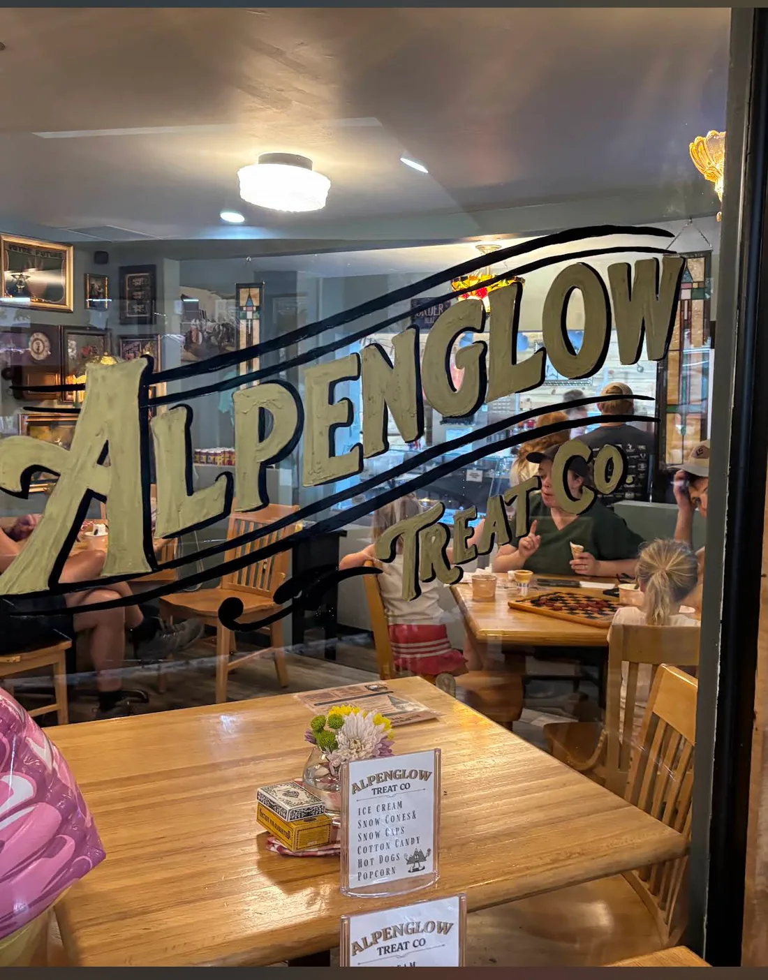 Alpenglow Treat Co window lettering with the shop seating visible behind it